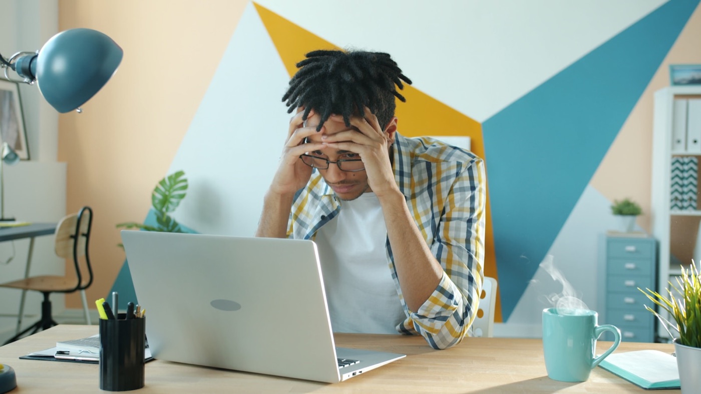 A job hunter with his head in his hands, waiting on replies that never come