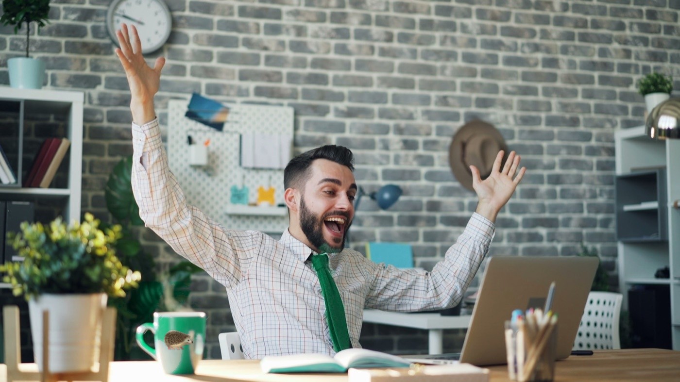 A job hunter celebrating at his laptop